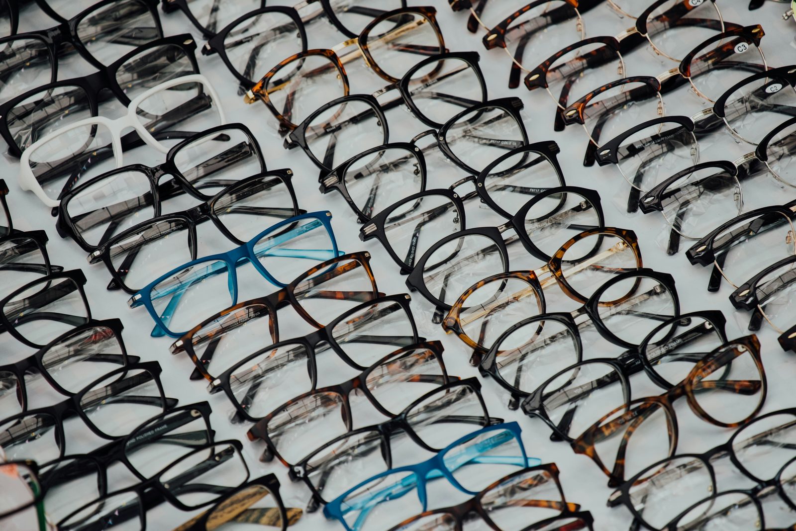 Dozens of eyeglass frames laid out in rows.